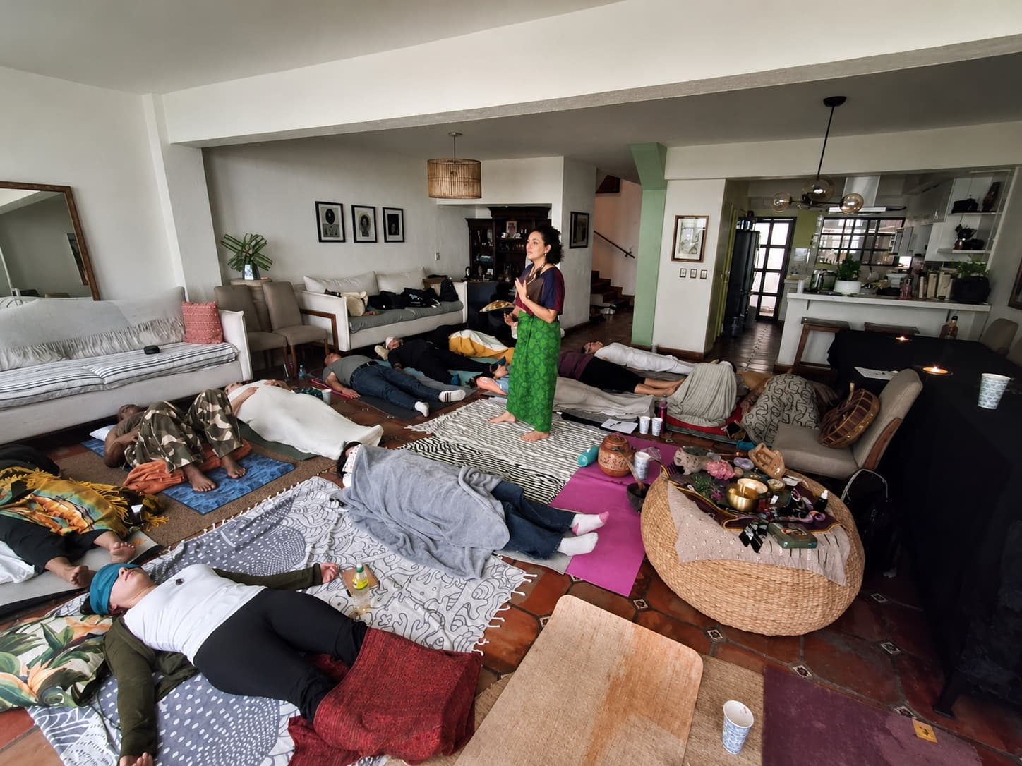 Asha standing and guiding a cacao ceremony, with participants lying on mats around her.